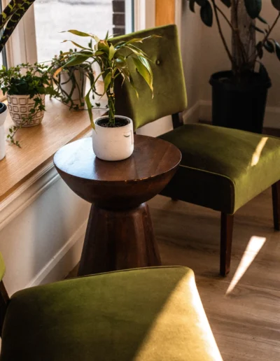 Waiting are with two green chairs and a round walnut-wood table