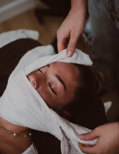 Woman with white towel wrapped around face after receiving facial